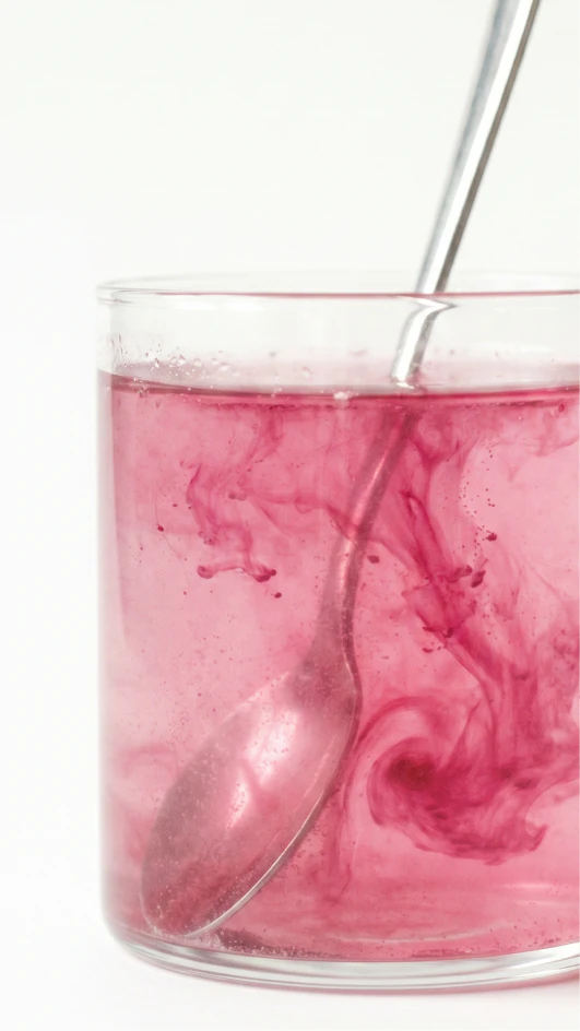 Bright pink wellness drink swirling around a silver straw.
